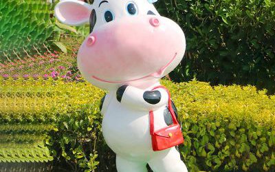 花園里一只拿包的玻璃鋼彩繪卡通仿真動(dòng)物牛雕塑